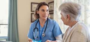 A nurse attentively converses with an elderly woman, providing medical care and support.